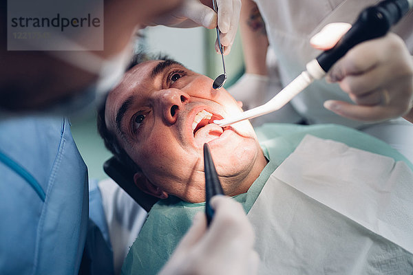 Zahnarzt schaut in den Mund eines männlichen Patienten  Ansicht von oben