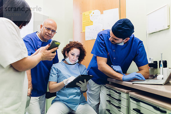 Zahnärzte in der Zahnarztpraxis schauen auf digitales Tablet  Laptop und Smartphone