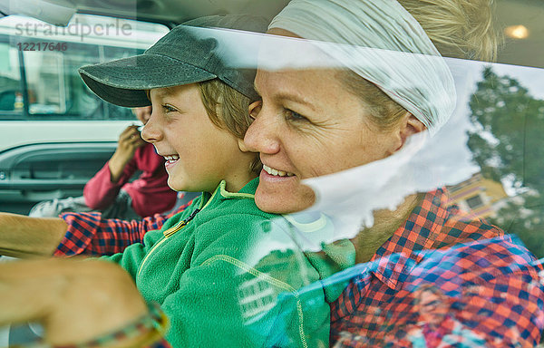 Mutter und Söhne im Fahrzeug  lächelnd  Blick durchs Fenster