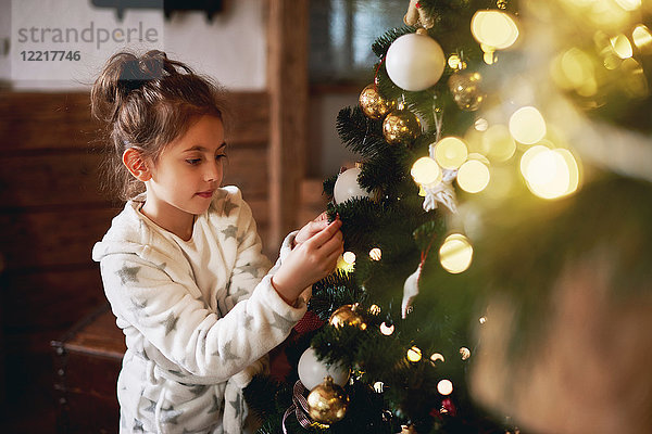 Junges Mädchen schmückt Weihnachtsbaum