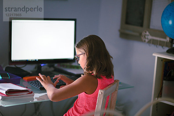 Junges Mädchen sitzt am Schreibtisch  macht Hausaufgaben  benutzt den Computer