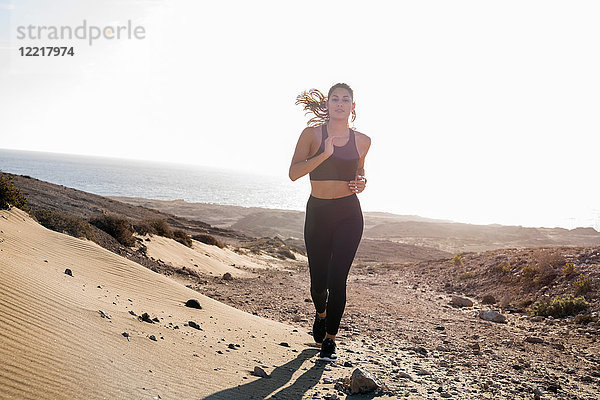 Junge Läuferin läuft in trockener Küstenlandschaft  Las Palmas  Kanarische Inseln  Spanien