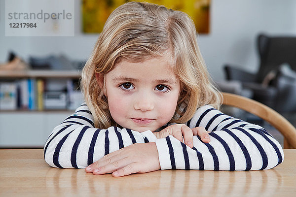 Porträt eines jungen Mädchens  am Tisch sitzend  nachdenklicher Ausdruck