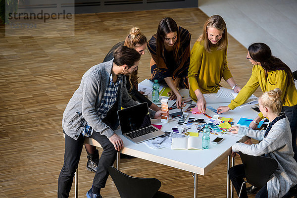 Team von Designerinnen und Designern diskutiert Farbmuster auf dem Tisch des Designstudios