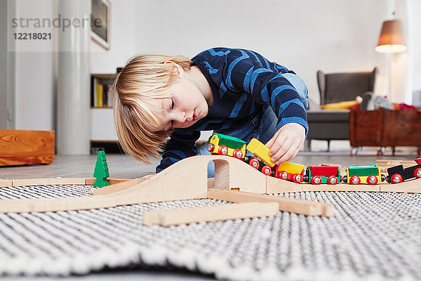 Junge spielt mit Spielzeugeisenbahn und Schienen