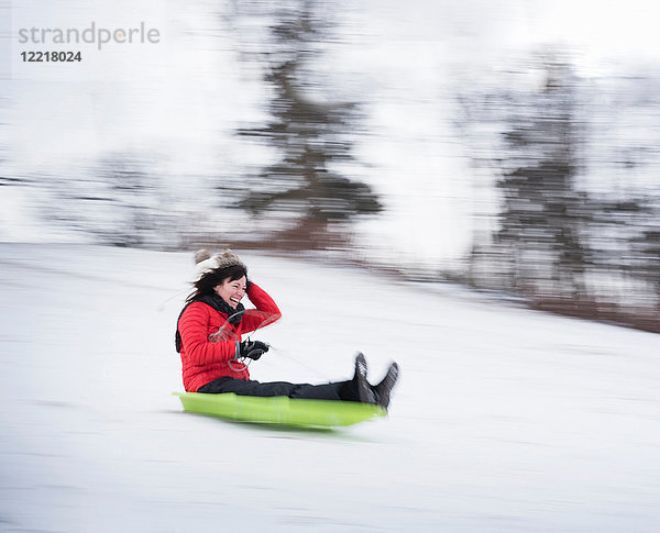 Schlitten fahrende Frau auf verschneitem Hügel