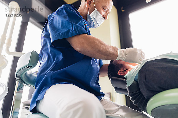Zahnarzt führt zahnärztlichen Eingriff an männlichem Patienten durch