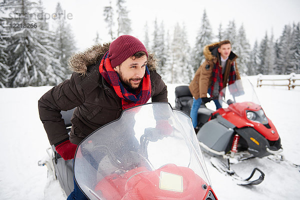 Junge Männer fahren im Winter auf Schneemobilen