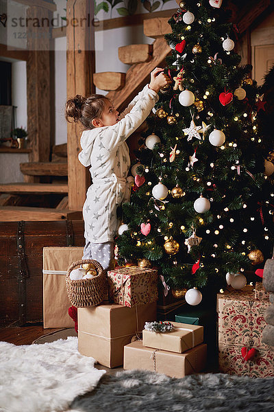 Junges Mädchen schmückt Weihnachtsbaum