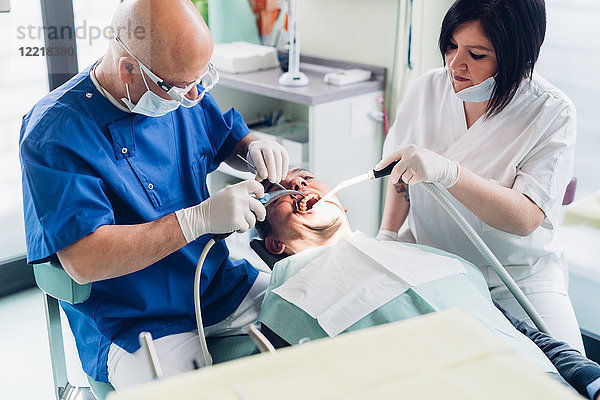 Zahnarzt und Zahnarzthelferin führen Verfahren an männlichen Patienten durch