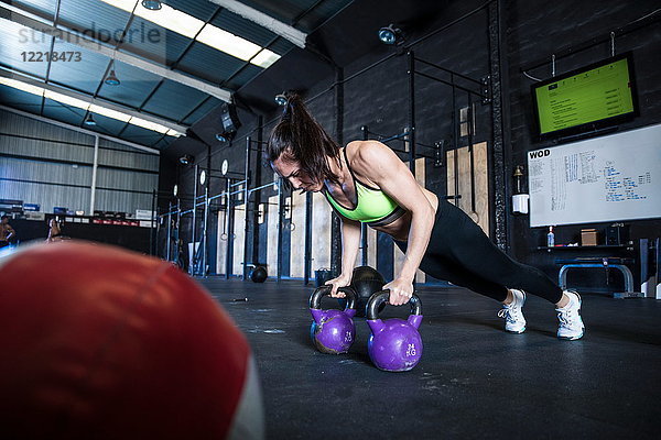 Frau beim Turnen in der Turnhalle  mit Kettlebells