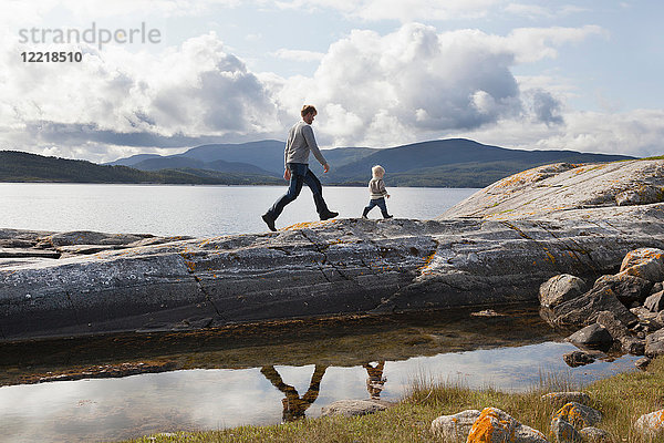 Mann und Sohn wandern auf einer Felsformation im Fjord  Aure  More og Romsdal  Norwegen