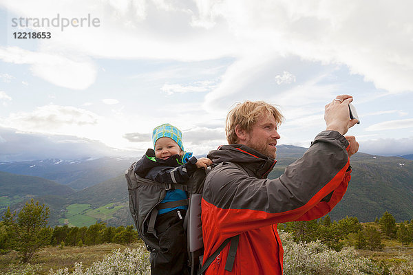 Männlicher Wanderer mit Sohn fotografiert Berglandschaft  Jotunheimen-Nationalpark  Lom  Oppland  Norwegen