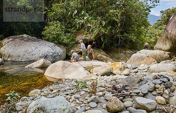 Vater und Söhne entspannen sich auf Felsen am Wasser  Ventilla  La Paz  Bolivien  Südamerika