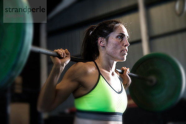 Frau übt im Fitnessstudio  mit Langhantel