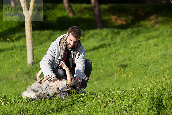 Mann spielt mit Hund im Parkgras
