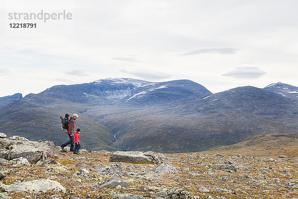 Mann mit Söhnen beim Wandern in der Berglandschaft  Jotunheimen-Nationalpark  Lom  Oppland  Norwegen
