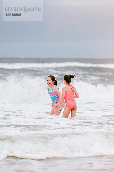 Zwei Mädchen stehen in den Wellen des Ozeans  Dauphin Island  Alabama  USA