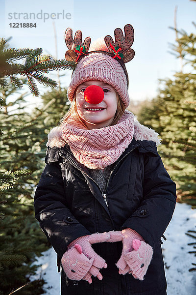 Mädchen im Weihnachtsbaumwald mit roter Nase  Portrait