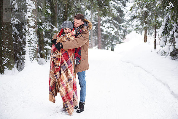 Junges Paar umarmt sich im Schnee