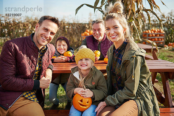Porträt einer Drei-Generationen-Familie am Kürbisbeet-Picknicktisch
