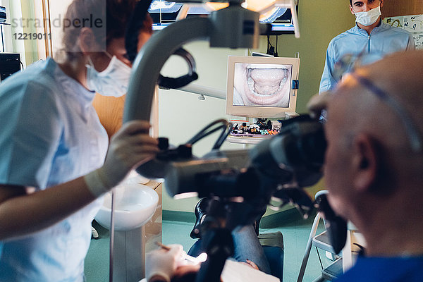 Zahnarzt und Zahnarzthelferin führen Verfahren am Patienten durch