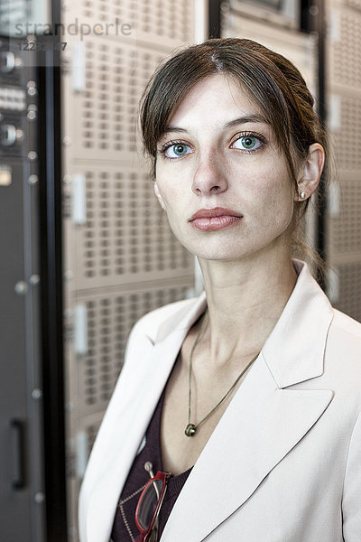 Porträt einer Technikerin  die in einem großen Computer-Serverraum arbeitet.