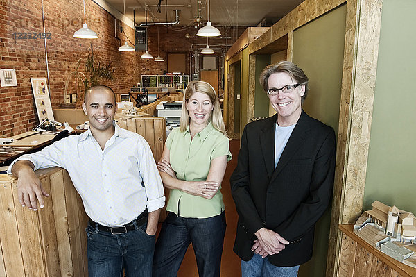 Porträt eines multiethnischen Teams von drei Architekten in einem kleinen Büro.