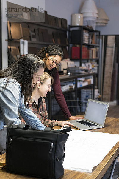 Drei Frauen versammelten sich um einen Tisch im Bürobereich einer Metallwerkstatt.