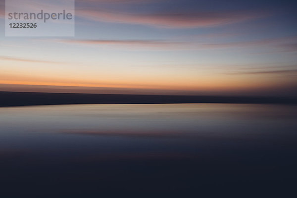 Seelandschaft mit bewölktem Himmel bei Sonnenuntergang.