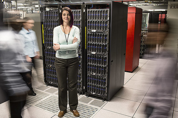 Kaukasische Technikerin  die in einem Gang einer großen Computer-Serverfarm steht.