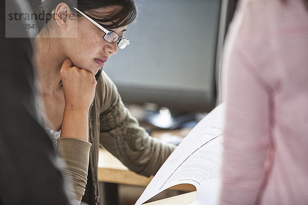 Asiatische Frau leitet ein informelles Treffen in einem kreativen Büro.