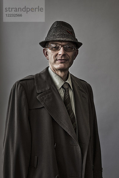 Studioporträt eines kaukasischen männlichen Schauspielers mit Hut und Mantel.