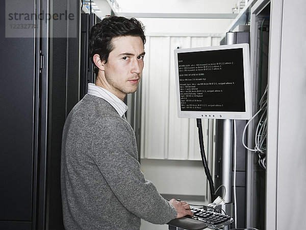 Kaukasischer männlicher Techniker  der auf Computerservern in einer Computerserverfarm arbeitet.