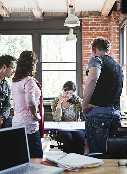 Eine gemischtrassige Gruppe von Leuten trifft sich zum Brainstorming eines Themas in einem kreativen Büro.