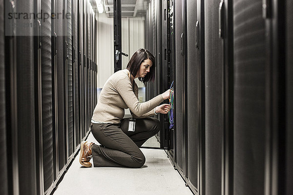 Kaukasische Technikerin  die auf Computerservern in einer Serverfarm arbeitet.