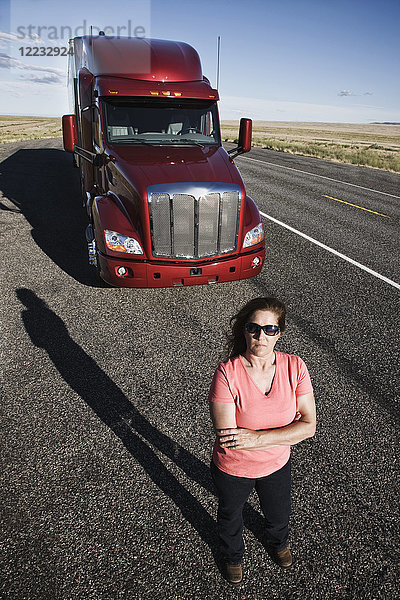 Porträt einer kaukasischen Fahrerin und ihres Lastwagens.