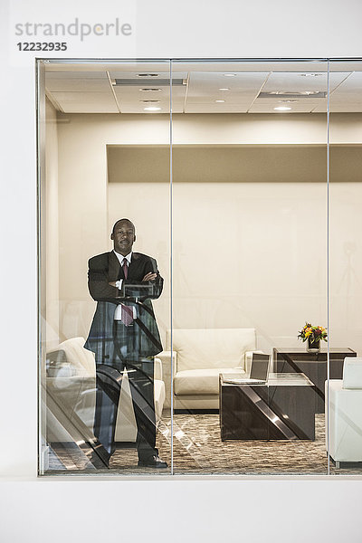 Schwarzer Geschäftsmann steht im Fenster des Konferenzraums.