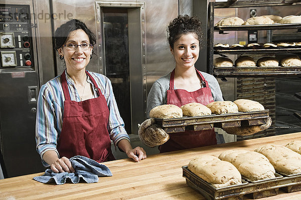 Bäckerinnen  die in einer Bäckerei mit Brotlaiben arbeiten.