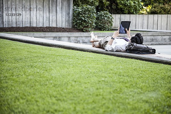 Geschäftsmann in einem Stadtpark in der Innenstadt macht eine Pause und überprüft sein Computer-Notebook