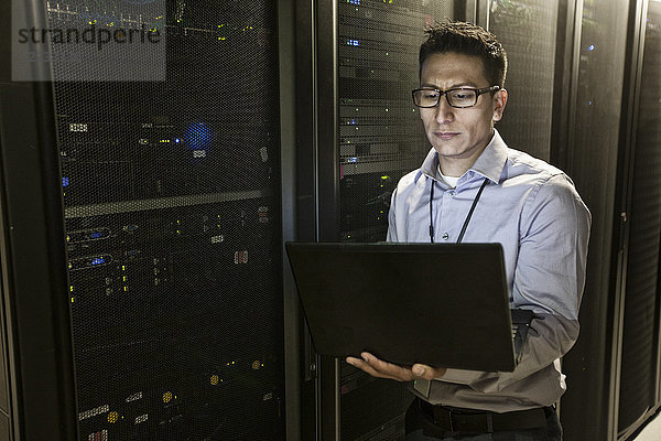 Hispanoamerikanischer Techniker  der Diagnosetests auf Computerservern in einer großen Serverfarm durchführt.