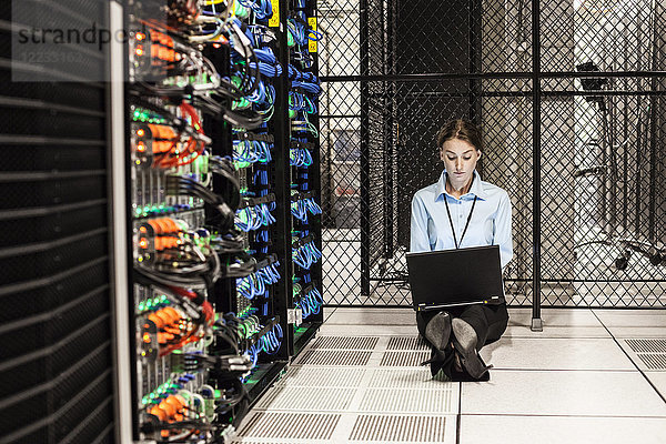 Kaukasische Technikerin  die auf Computerservern in einer Serverfarm arbeitet.