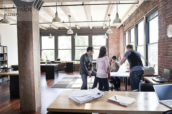 Eine gemischtrassige Gruppe von Leuten trifft sich zum Brainstorming eines Themas in einem kreativen Büro.