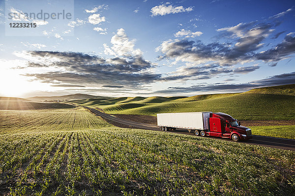 Kommerzieller Lastwagen fährt bei Sonnenuntergang durch Ackerland im Osten Washingtons  USA.