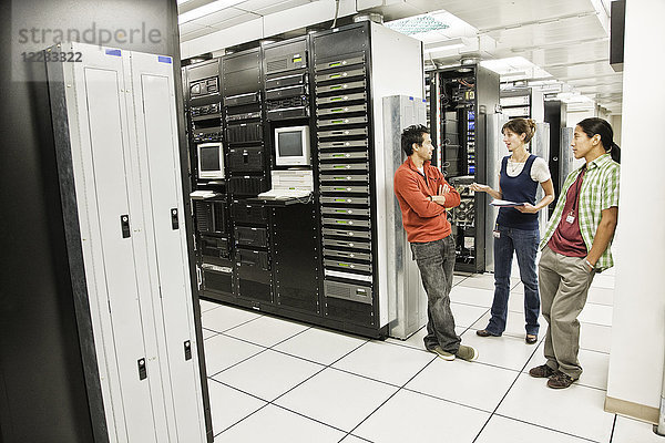 Drei multiethnische Techniker arbeiten in einem großen Computer-Serverraum.