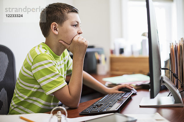 Junger kaukasischer Junge bei der Arbeit an einem Desktop-Computersystem.