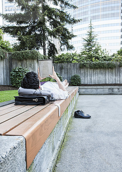 Geschäftsmann in einem Stadtpark in der Innenstadt macht eine Pause und überprüft sein Computer-Notebook