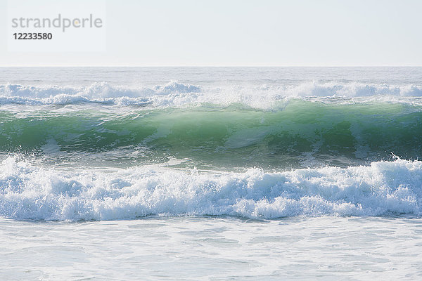 Meereslandschaft mit brechenden Wellen am Sandstrand.