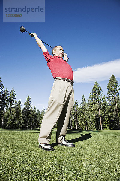 Älterer Golfer  der sich mit einem Golfschläger streckt  bevor er eine Runde Golf spielt.