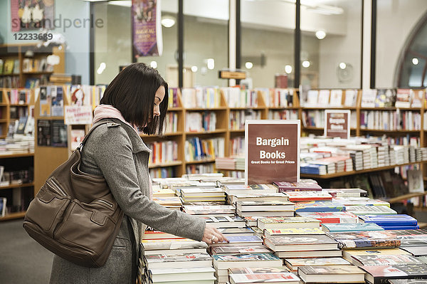 Kaukasische Frau blättert in einem Buchladen in Büchern.